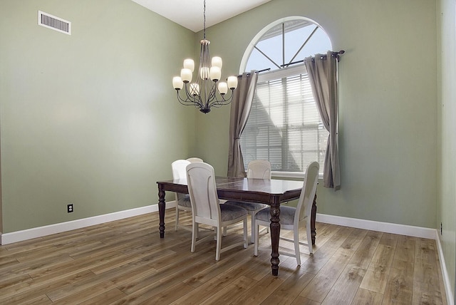 dining space with light wood-style floors, a chandelier, visible vents, and baseboards