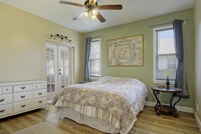 bedroom featuring light wood finished floors, baseboards, ceiling fan, access to outside, and french doors