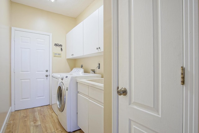 washroom with light wood-type flooring, cabinet space, and washing machine and clothes dryer