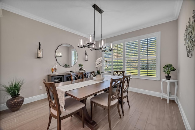 dining room with ornamental molding, light wood-type flooring, a notable chandelier, and baseboards