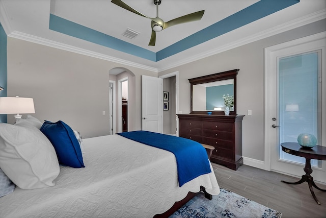 bedroom featuring arched walkways, ceiling fan, wood finished floors, visible vents, and a raised ceiling