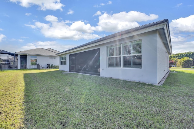 back of property featuring a yard, a sunroom, and stucco siding