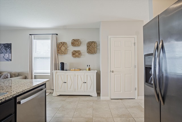 kitchen featuring light tile patterned floors, stainless steel appliances, baseboards, and light stone countertops