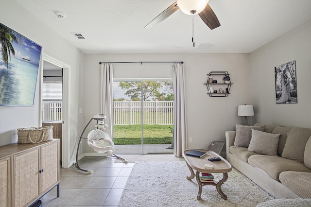 living area featuring a wealth of natural light, visible vents, ceiling fan, and light tile patterned floors