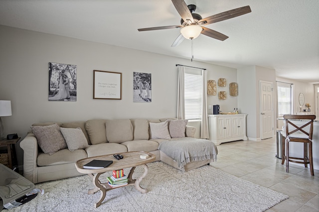 living area with a ceiling fan, baseboards, and light tile patterned floors