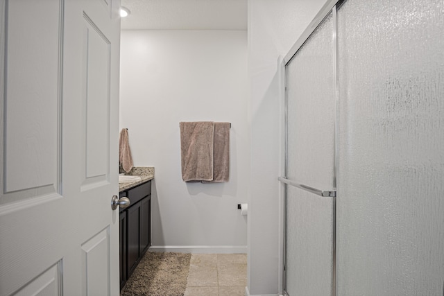 full bathroom with a stall shower, tile patterned flooring, vanity, and baseboards