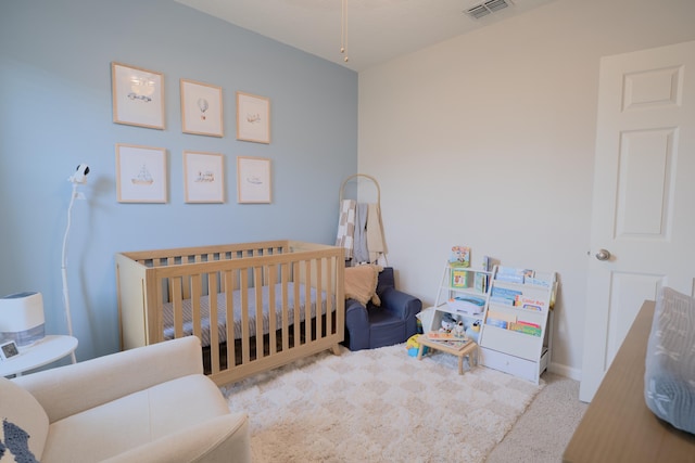 carpeted bedroom featuring a crib, visible vents, and baseboards