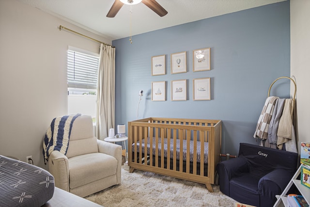 bedroom with a nursery area, carpet, and a ceiling fan