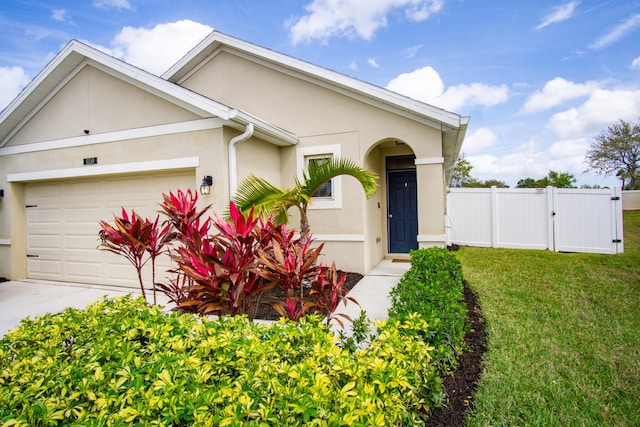 ranch-style house with a garage, a front yard, fence, and stucco siding