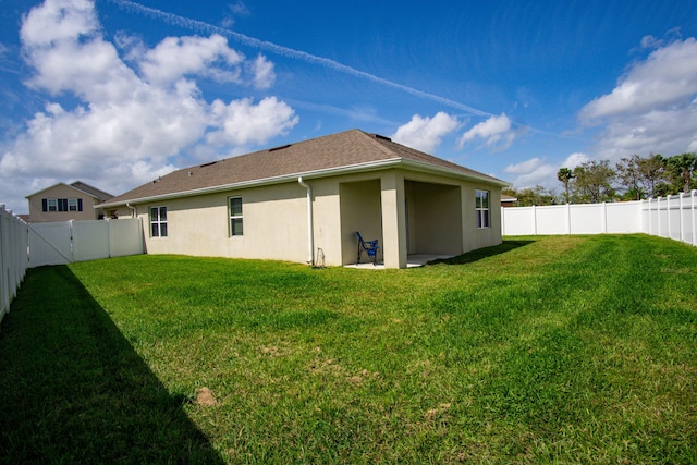 back of property with a lawn, a fenced backyard, and stucco siding