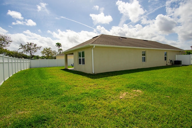 back of property with stucco siding, a fenced backyard, cooling unit, and a yard