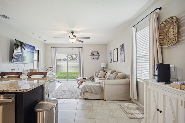 living area with a ceiling fan, visible vents, and light tile patterned flooring