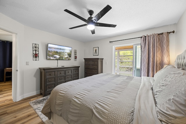 bedroom with baseboards, ceiling fan, light wood-style flooring, and a textured ceiling