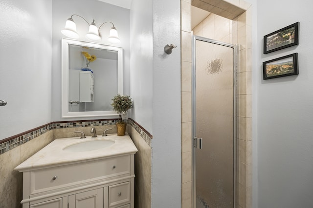 full bath with a stall shower, vanity, and tile walls