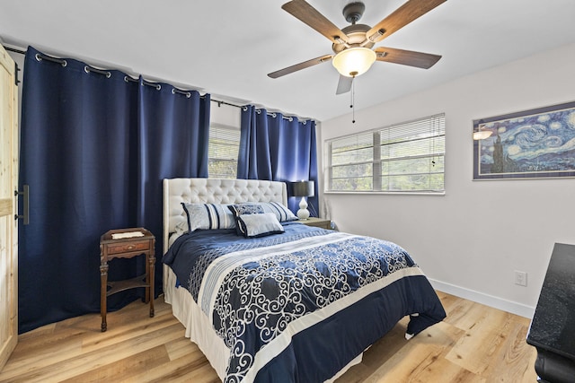 bedroom featuring a ceiling fan, multiple windows, baseboards, and wood finished floors