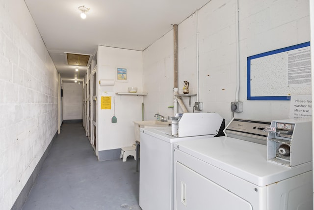 shared laundry area featuring concrete block wall and independent washer and dryer