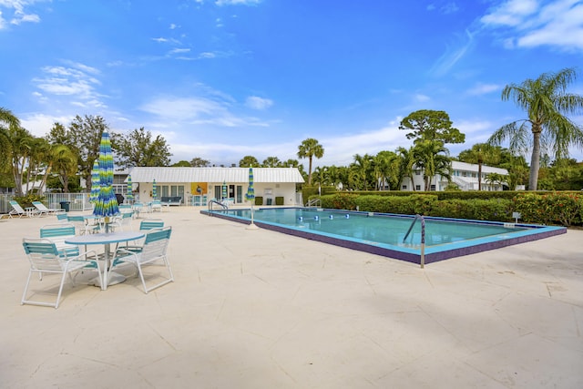 community pool with a patio and fence