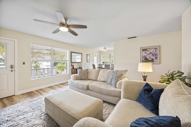 living area with a textured ceiling, a wealth of natural light, wood finished floors, and visible vents