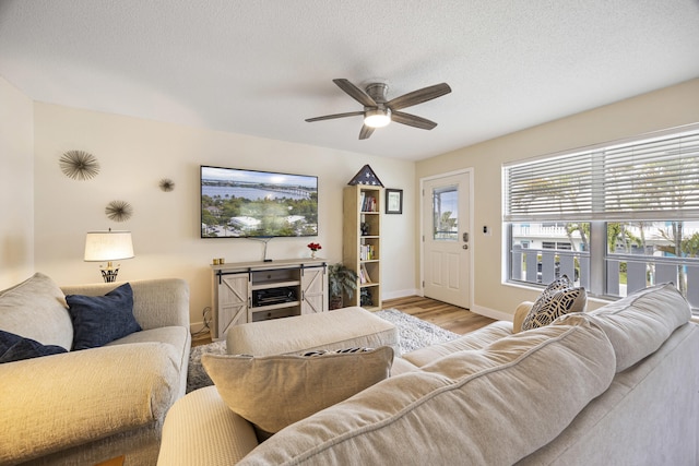 living room featuring a textured ceiling, wood finished floors, a ceiling fan, and baseboards