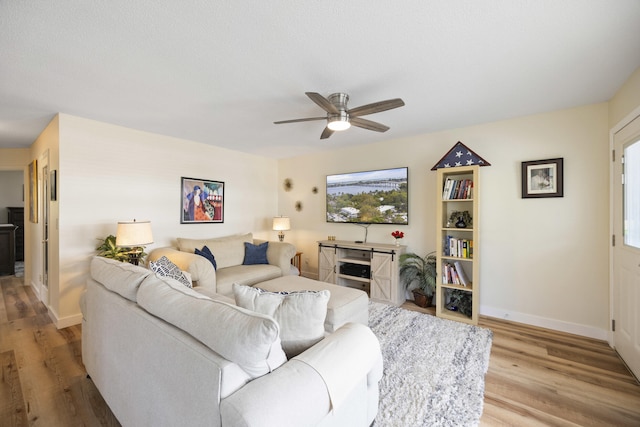 living room with baseboards, ceiling fan, and light wood-style floors