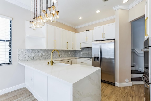 kitchen featuring light countertops, black cooktop, light wood-type flooring, stainless steel fridge, and a peninsula