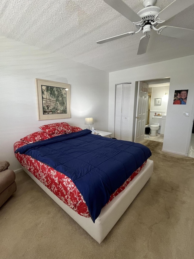 carpeted bedroom with a textured ceiling, connected bathroom, a ceiling fan, baseboards, and a closet