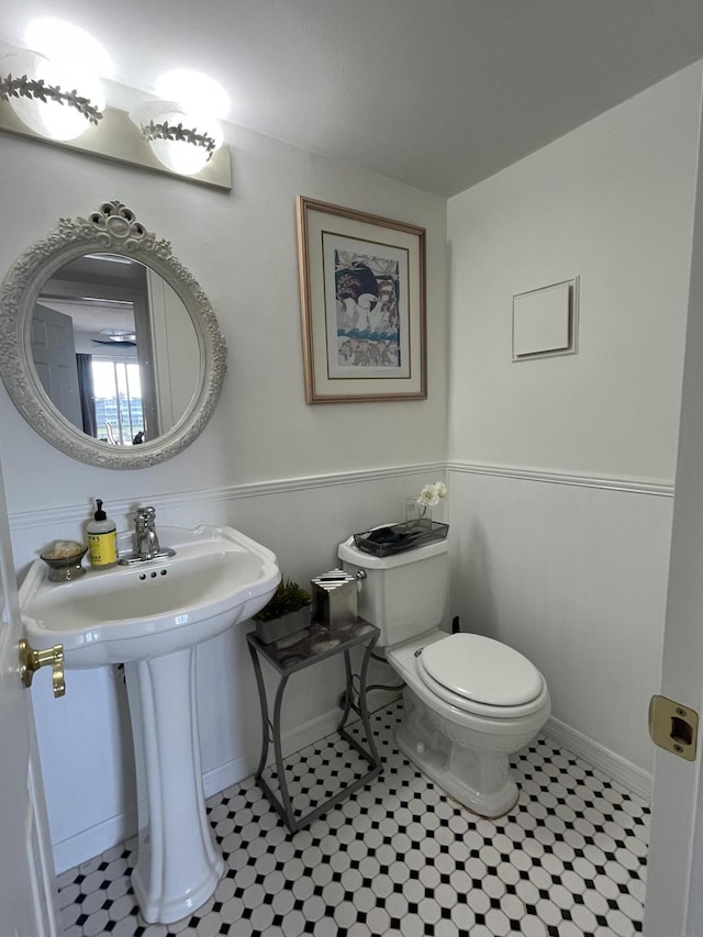 half bath with toilet and a wainscoted wall