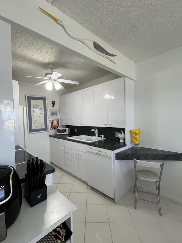 kitchen featuring white appliances, a textured ceiling, white cabinets, and a sink