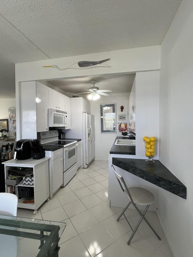 kitchen with a textured ceiling, white appliances, a sink, a ceiling fan, and dark countertops