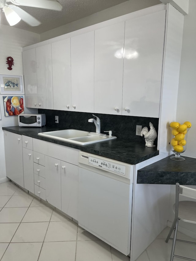 kitchen featuring dark countertops, white appliances, white cabinets, and a sink