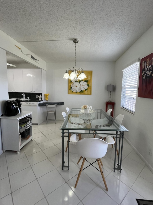 dining area with a chandelier, a textured ceiling, baseboards, and light tile patterned floors