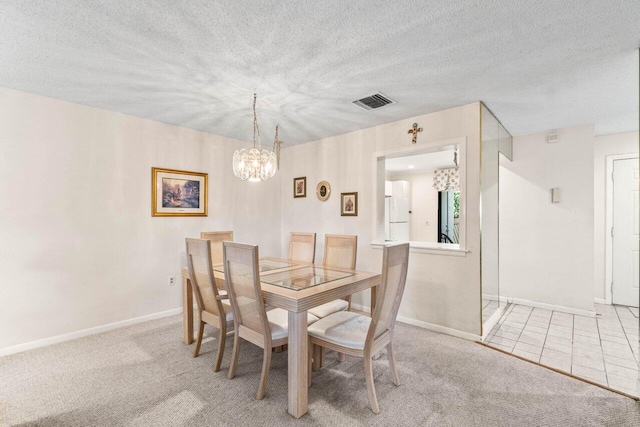 carpeted dining room featuring a chandelier, visible vents, a textured ceiling, and baseboards