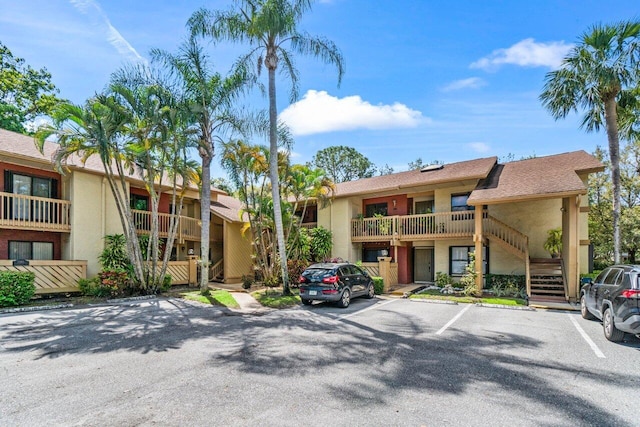 view of property featuring stairs and uncovered parking