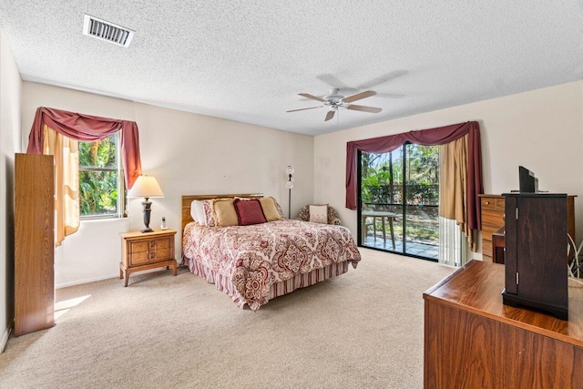 carpeted bedroom with access to exterior, multiple windows, visible vents, and a ceiling fan