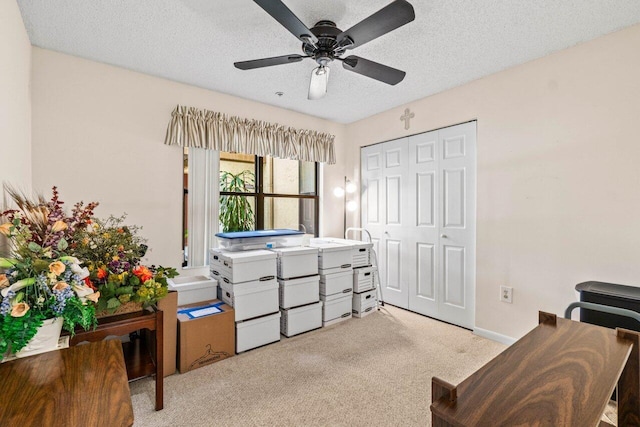 home office featuring carpet floors, a textured ceiling, baseboards, and a ceiling fan