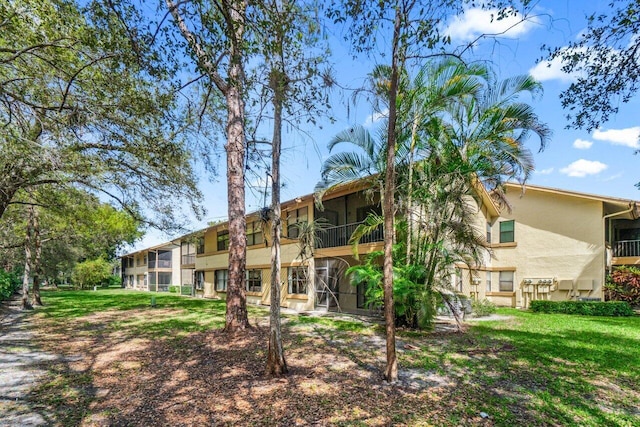 rear view of property with a lawn and stucco siding