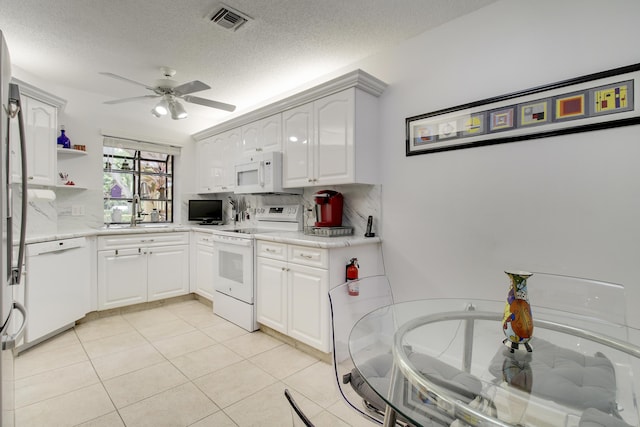 kitchen with light tile patterned flooring, visible vents, white appliances, a ceiling fan, and tasteful backsplash