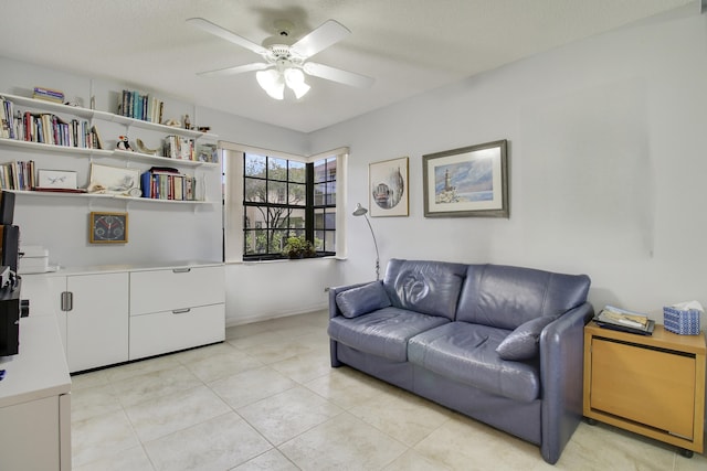 living room with light tile patterned floors, ceiling fan, baseboards, and a textured ceiling