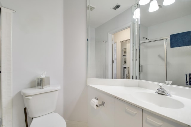 bathroom featuring visible vents, a shower with door, vanity, and toilet