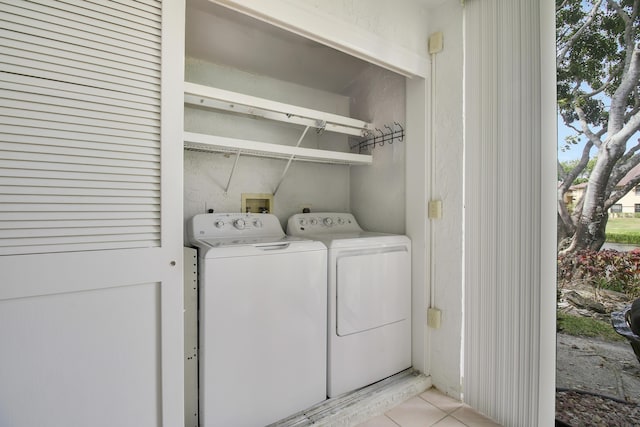 clothes washing area featuring light tile patterned floors, laundry area, and washing machine and clothes dryer