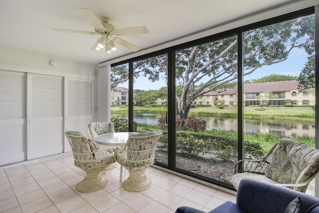 sunroom with a water view, a residential view, and a ceiling fan