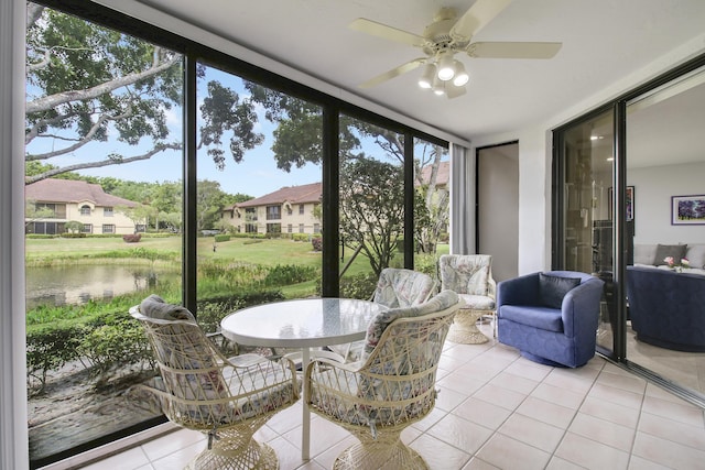 sunroom featuring a water view, a residential view, and a ceiling fan