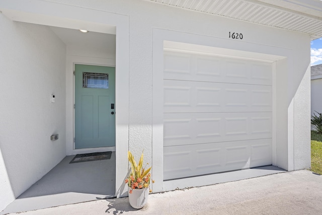 entrance to property with a garage and stucco siding