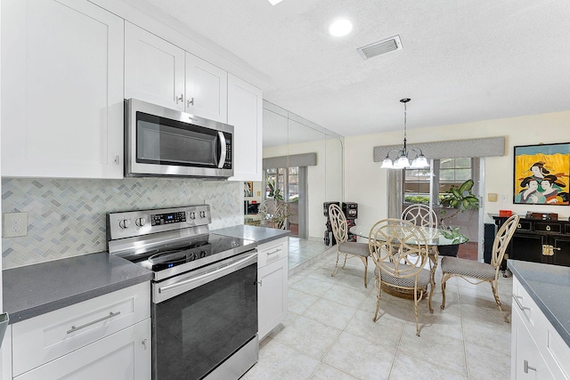 kitchen featuring stainless steel appliances, visible vents, backsplash, and white cabinetry