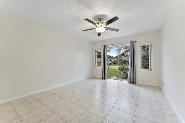 empty room featuring light tile patterned floors, baseboards, and a textured ceiling