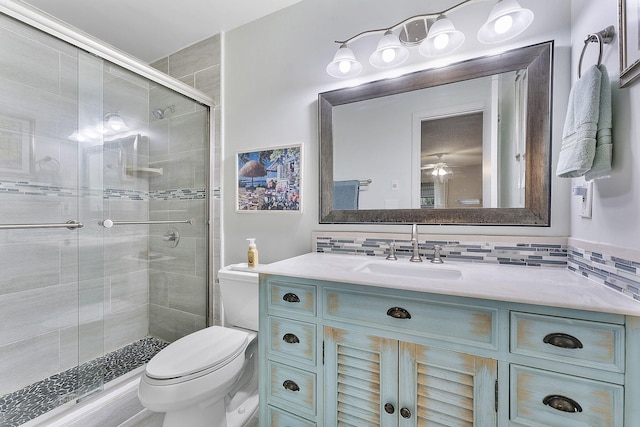 bathroom with tasteful backsplash, toilet, ceiling fan, a shower stall, and vanity