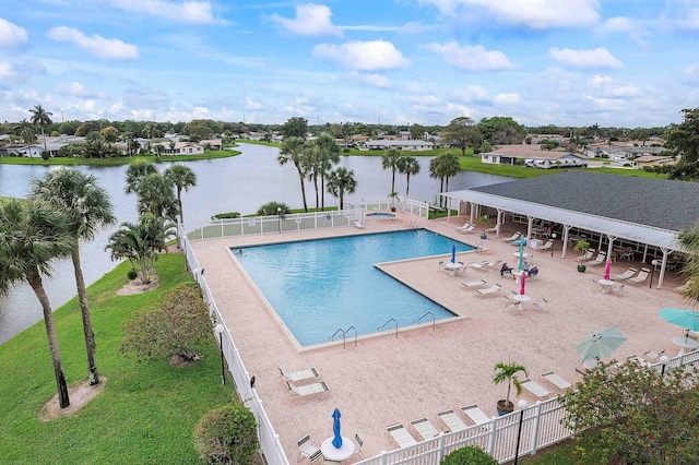 community pool with a patio area, a water view, and fence