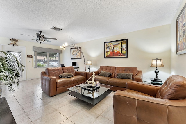 living room with light tile patterned floors, ceiling fan, visible vents, and a textured ceiling