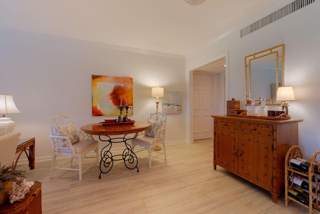 dining room featuring light wood-type flooring, visible vents, crown molding, and baseboards