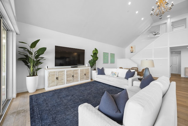 living area with baseboards, high vaulted ceiling, wood finished floors, and ceiling fan with notable chandelier